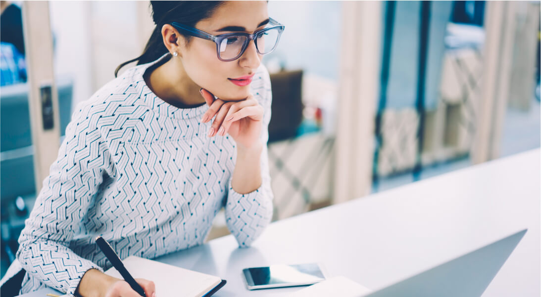 Woman focused on laptop screen taking notes