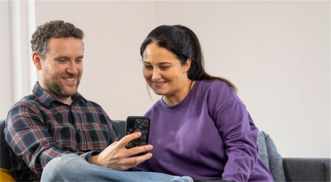 Couple smiling, looking at a phone screen