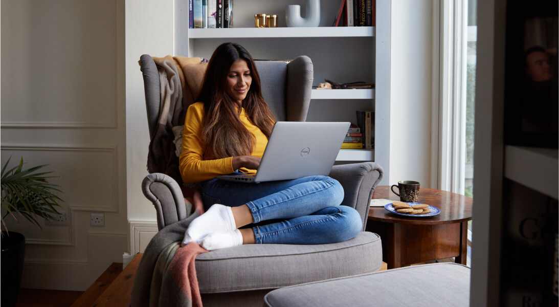 Woman relaxing on a couch with a laptop on her knees
