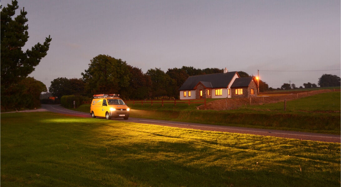Networks van passing in front of a house in the countryside