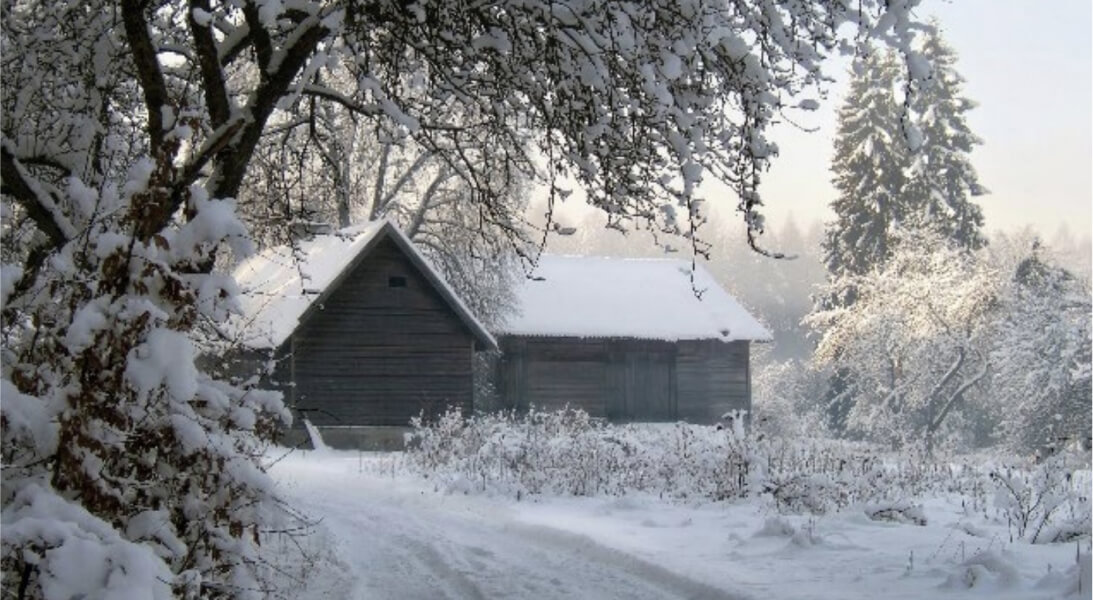 A snowy road winding through a winter landscape, leading to a wooden house nestled among the trees.