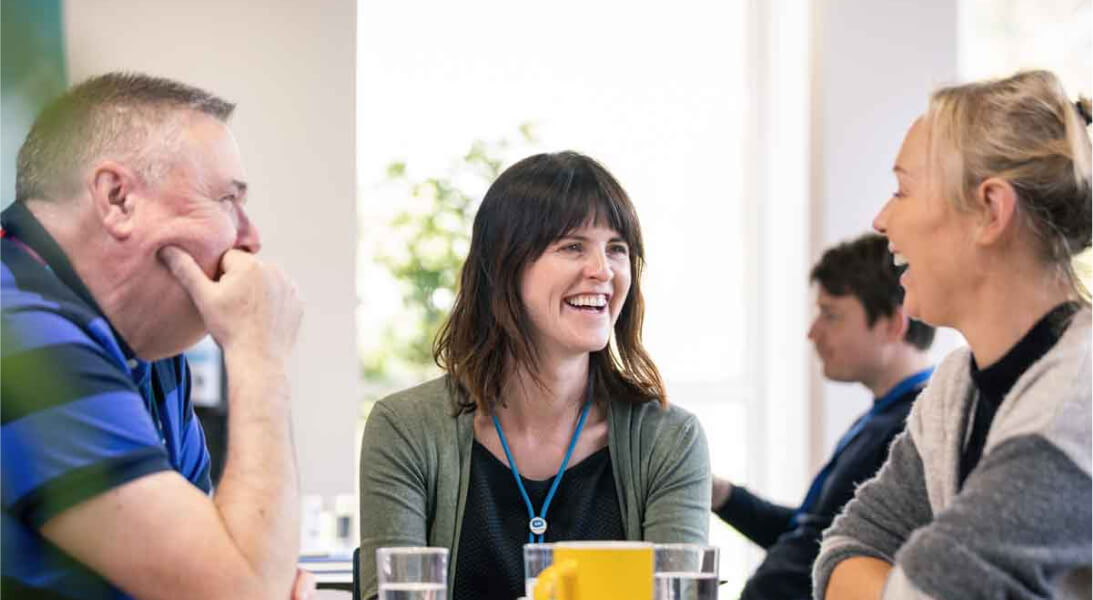 Staff sitting at a table and laughing