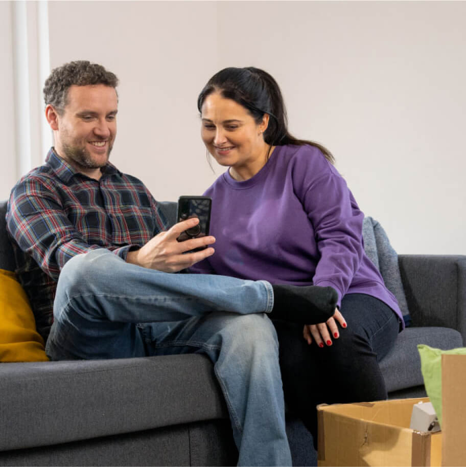 Happy couple sitting on a sofa looking at a phone