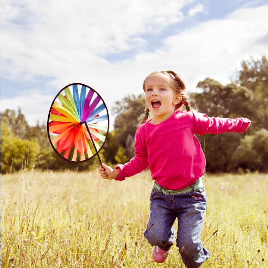 Little girl running in a field with a windmill