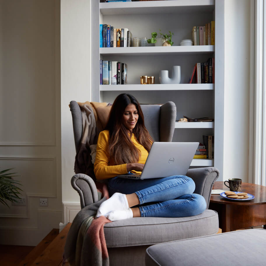 Woman relaxing on a couch with a laptop on her knees