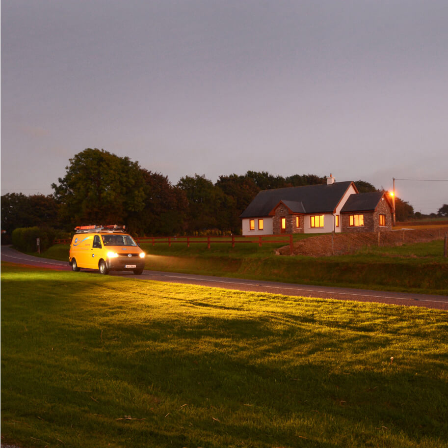 Networks van passing in front of a house in the countryside