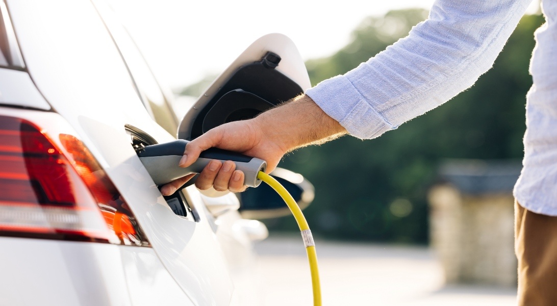 A man placing the EV charger into a car's charging port.