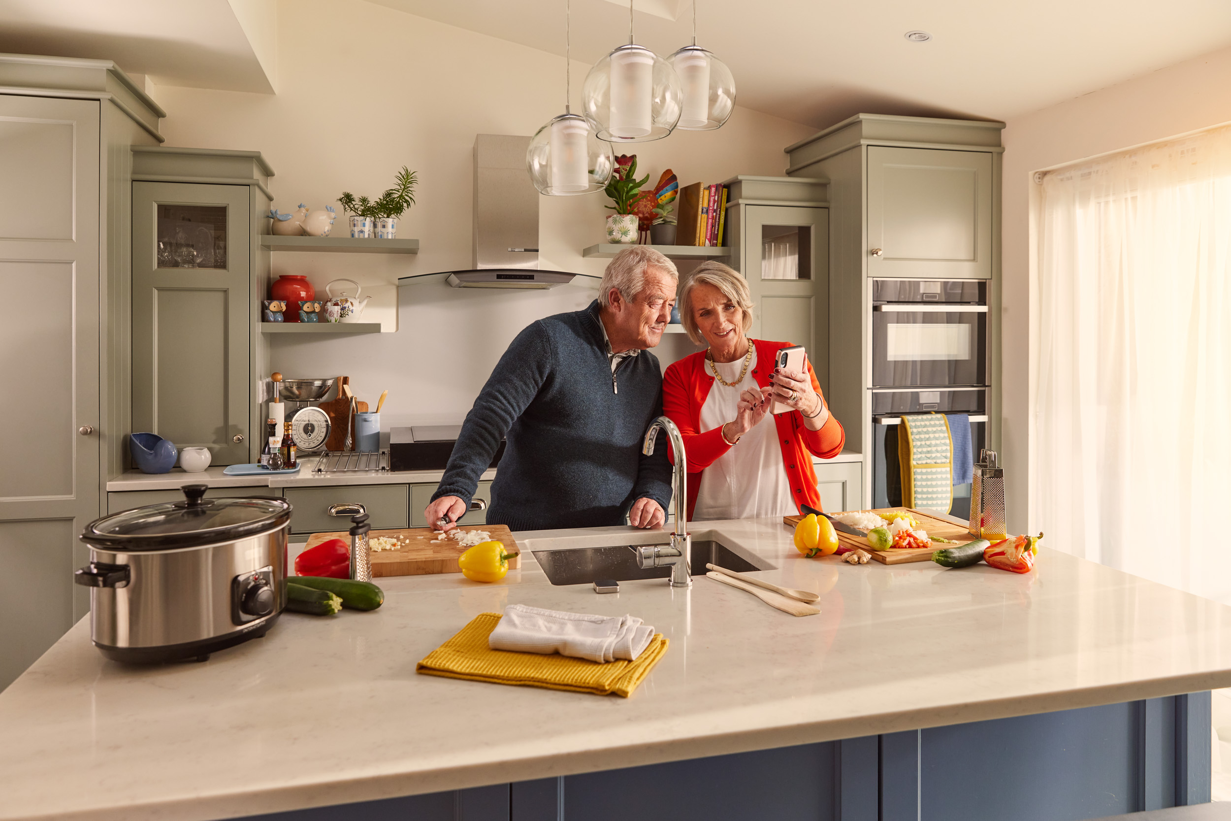 Two people in their kitchen looking at a phone.