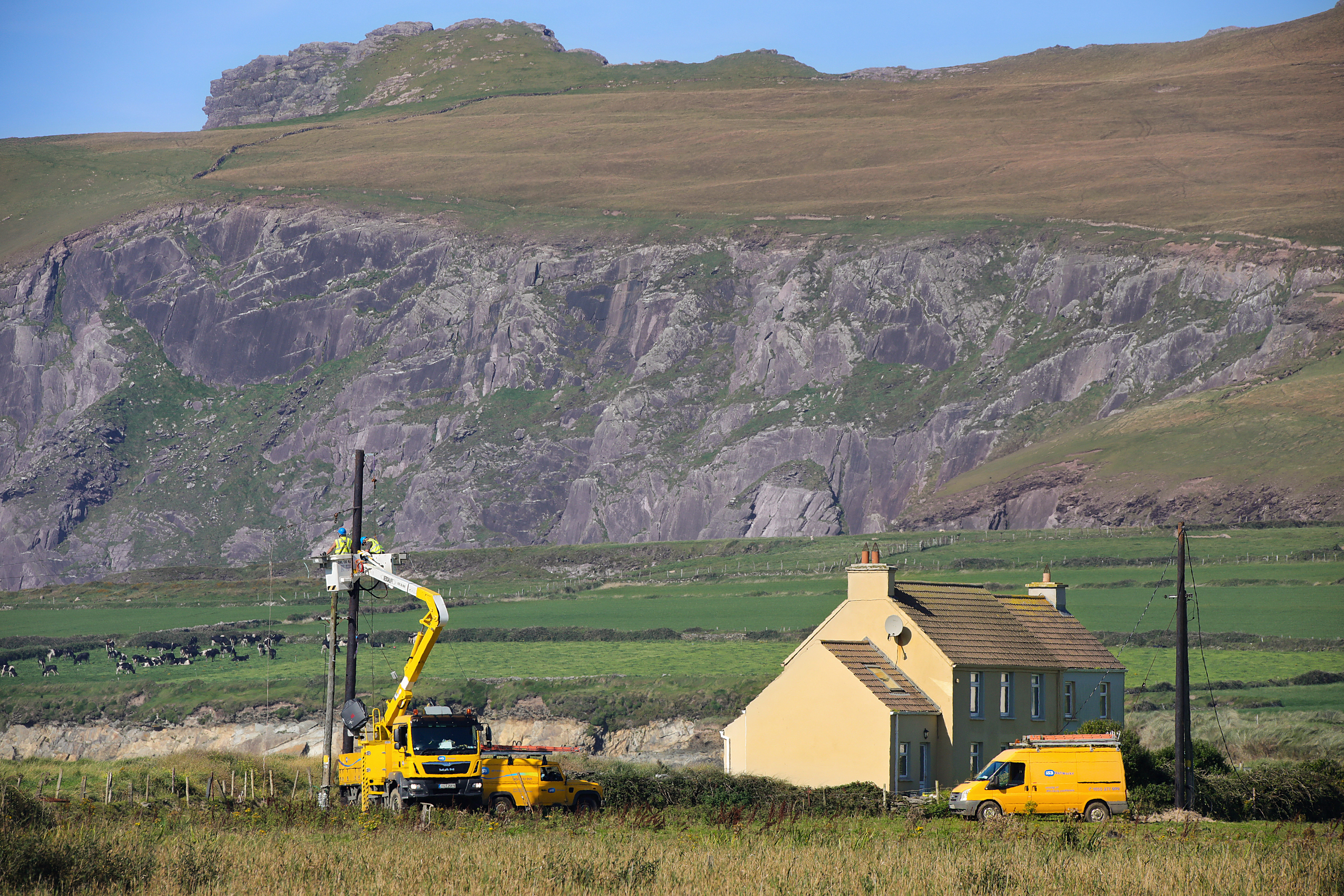 A group of network technicians using an aerial work platform to repair cables near a house